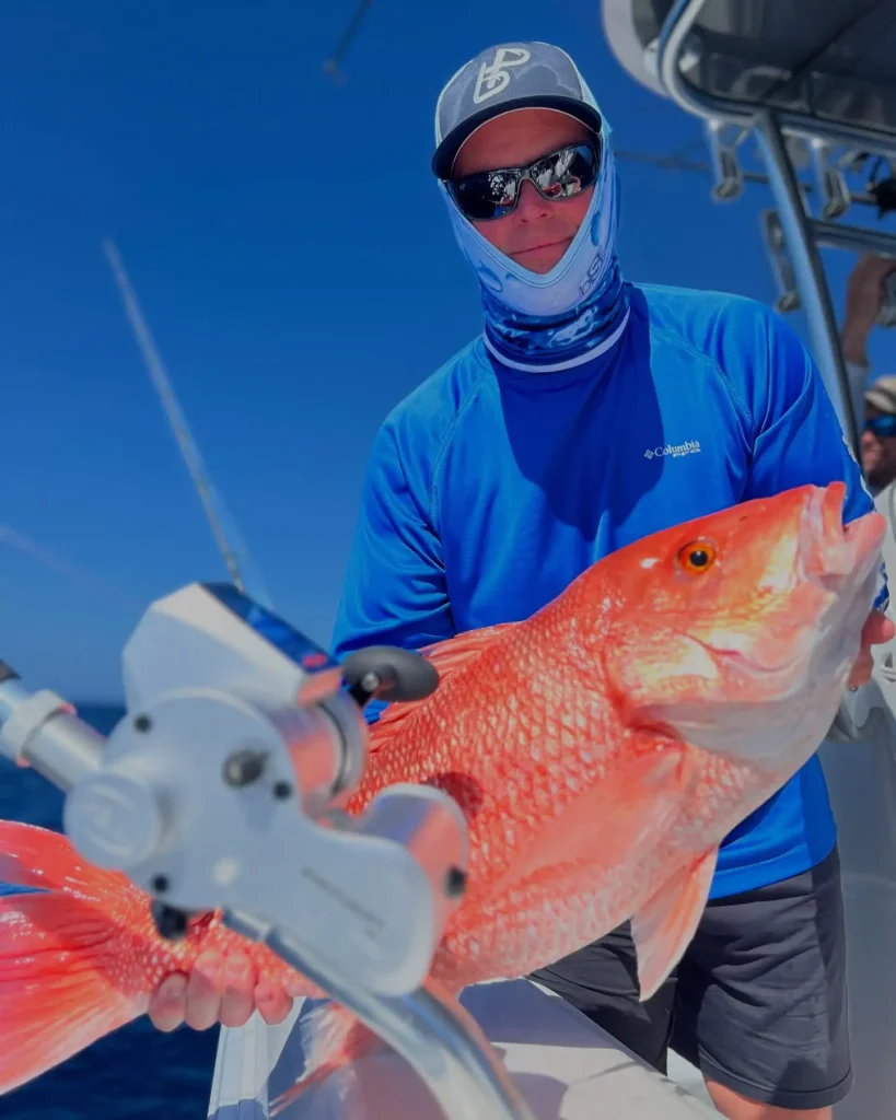 Customer holding a red snapper aboard a Charter Sauce fishing charter in Sarasota