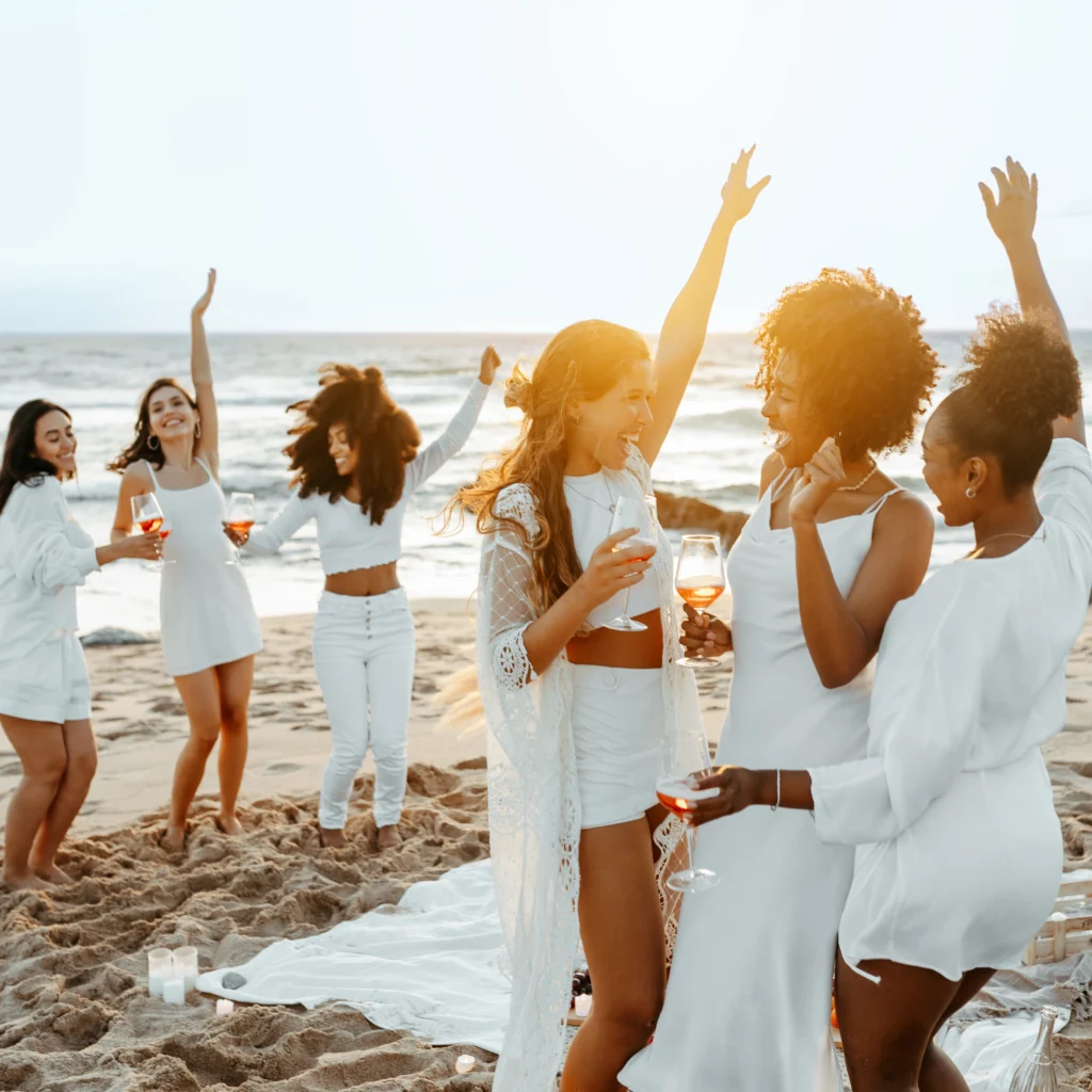 Bride celebrating with friends during a beachfront wedding reception at sunset in Sarasota, Florida.