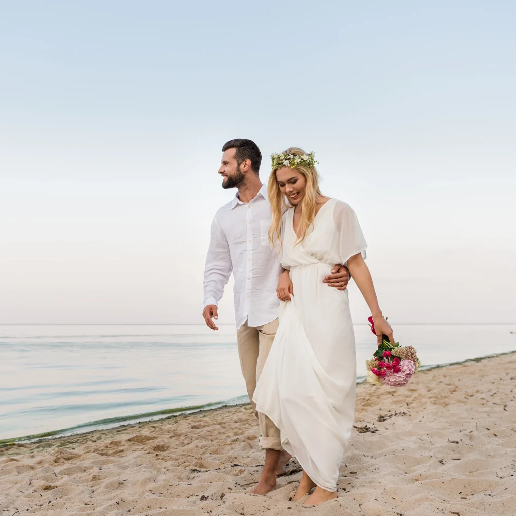 Newly married couple walking barefoot along a quiet Sarasota beach after their waterfront wedding ceremony at sunset.