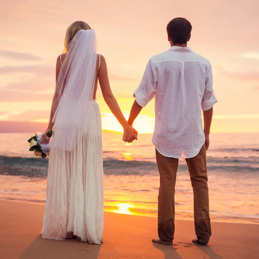 Bride and groom holding hands while watching the sunset on a Sarasota beach after their waterfront wedding ceremony.