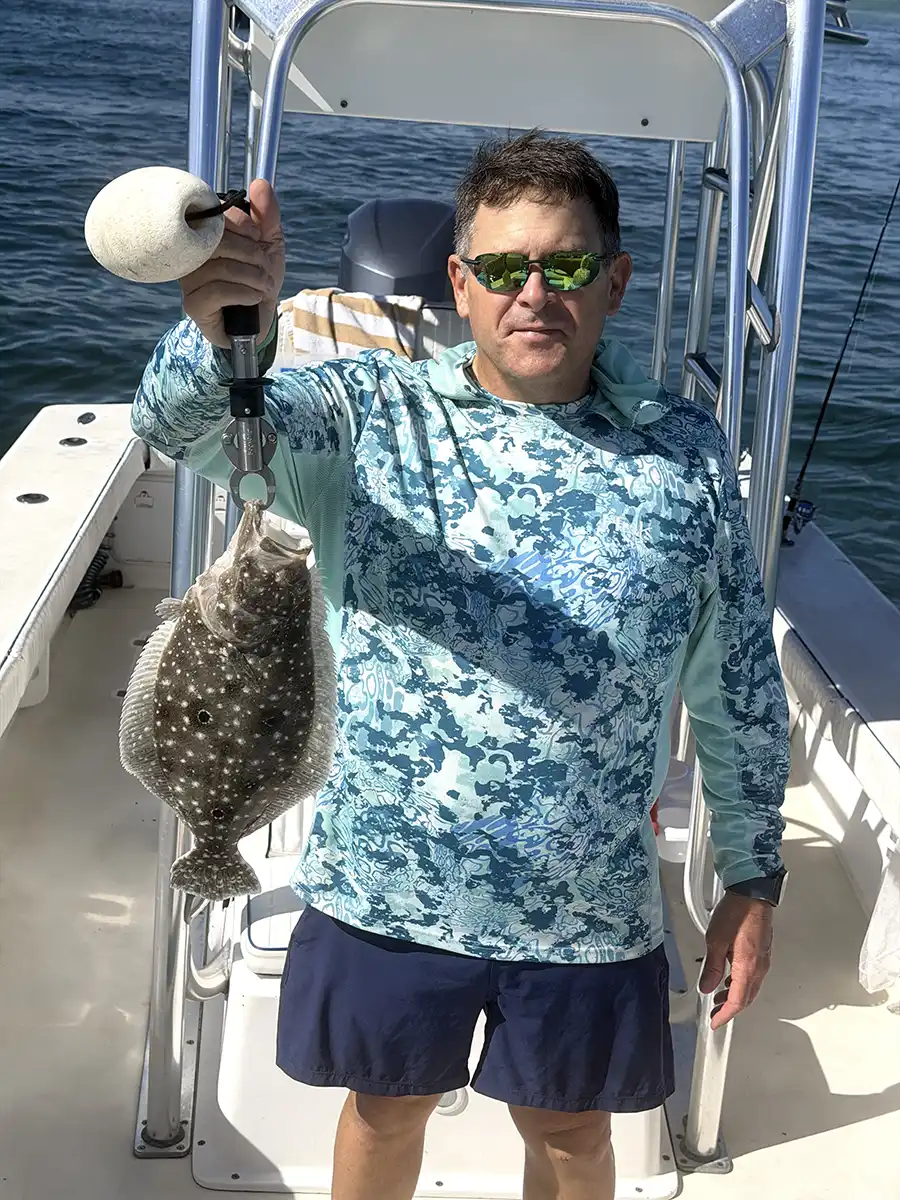 Angler holding a flounder aboard a fishing boat near Sarasota, Florida.