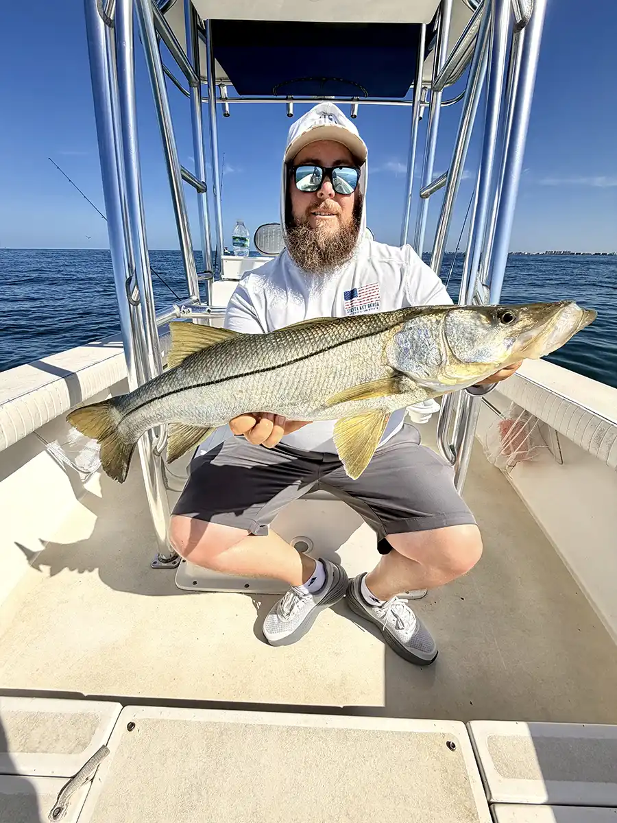 Angler holding a large snook aboard a fishing boat near Sarasota, Florida.