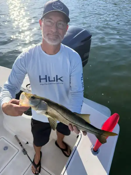 Angler holding a snook beside the boat while fishing in Sarasota, Florida